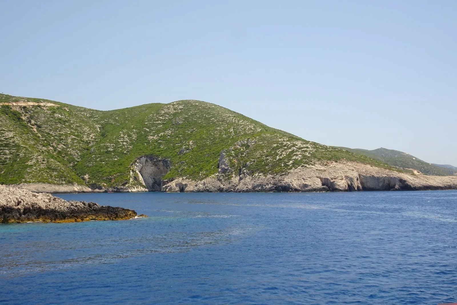 Rocky coastline with hills meeting the blue sea in Greece, similar to the Porto Limnionas landscape