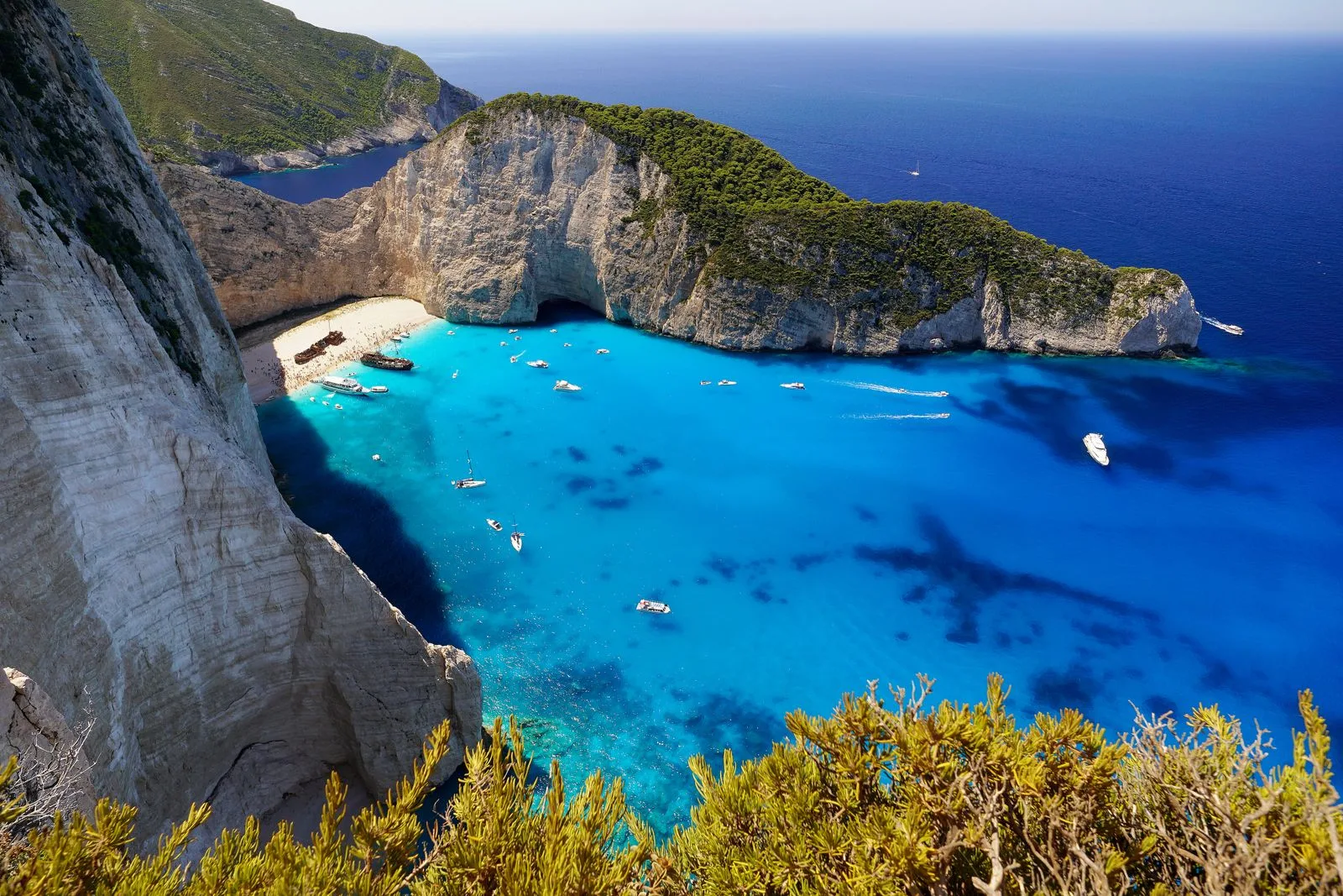 Overhead view of Navagio Beach showing turquoise waters, sandy shore, and surrounding cliffs in Greece