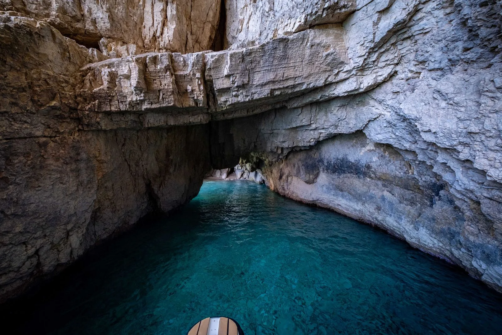 Inside a limestone sea cave with vibrant blue water, similar to the Blue Caves of Zakynthos